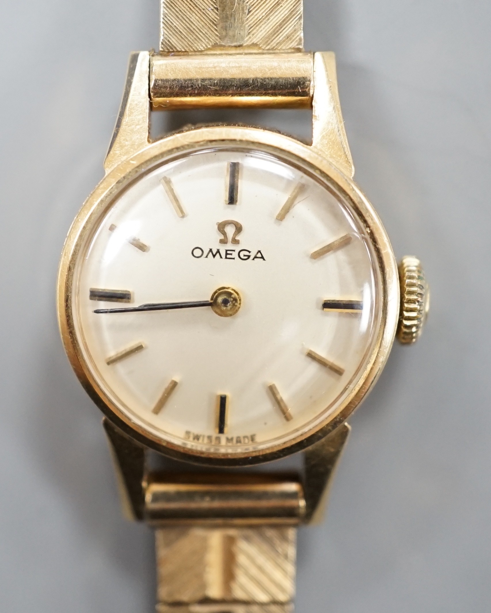 A lady's 9ct Omega manual wind wrist watch, on a 9ct gold bracelet